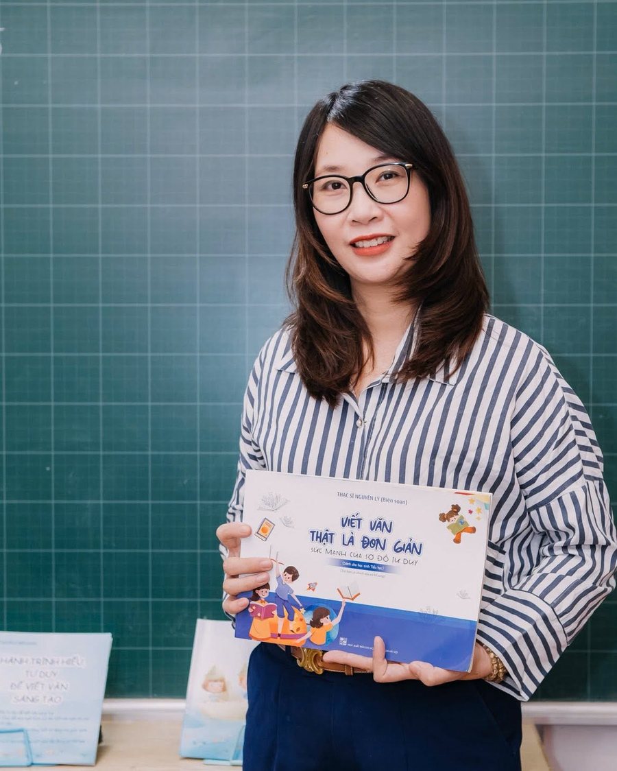 Cô Nguyên Lý cầm tài liệu đứng trước bảng